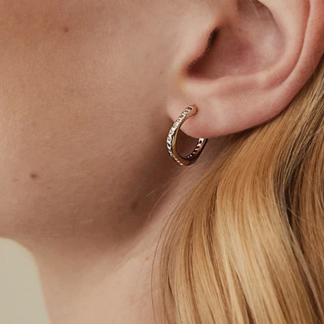 Why gold hoop earrings are a classic accessory worth investing in * woman wearing a gold hoop earring with zirconas